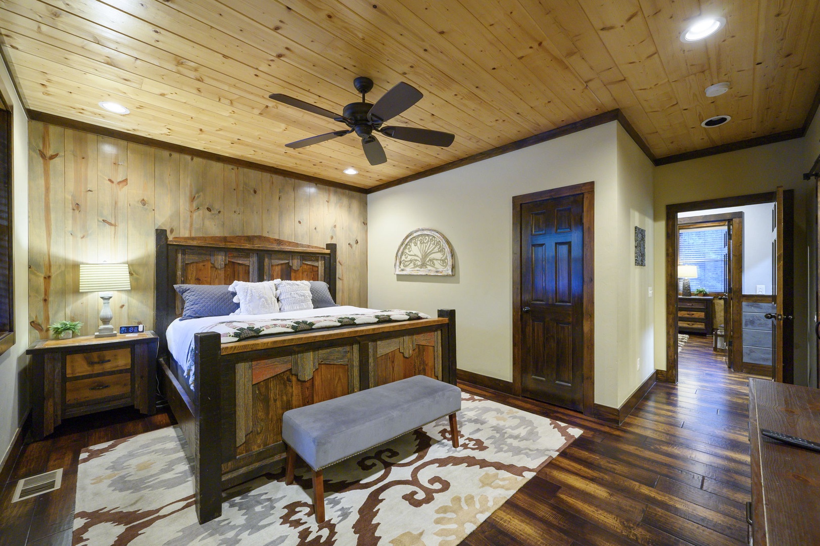 Rest easy in your inviting bedroom, where rustic wood meets modern comfort. Enjoy the soft glow of bedside lamps, a ceiling fan for gentle airflow, and rich hardwood floors underfoot—your personal retreat after a day of adventure.