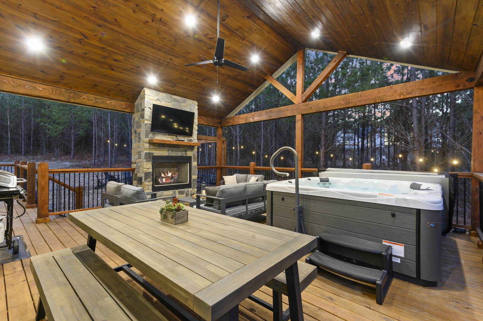 Unwind in your private covered deck with hot tub, outdoor fireplace, and cozy seating overlooking peaceful forest views.