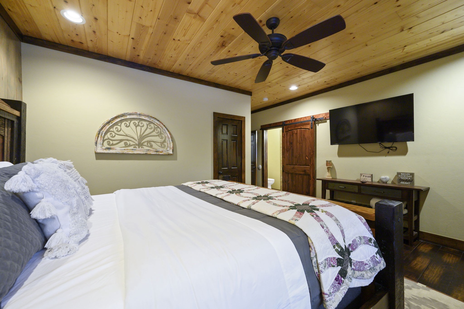 Drift off beneath a stunning wood ceiling and wake up to comfort. This cozy bedroom features a plush bed, rustic barn door detail, and all the charm you need for a restful stay.