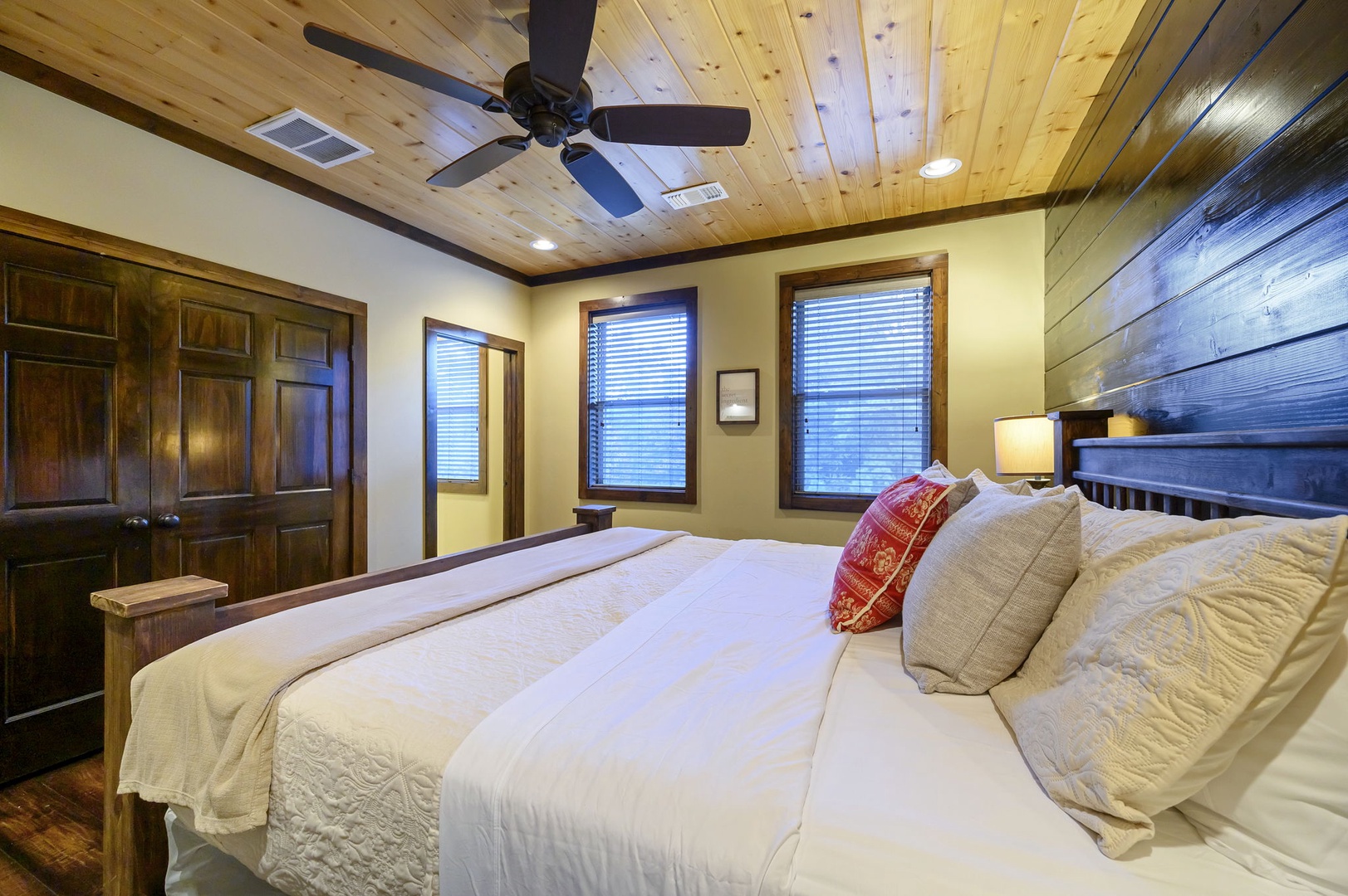 Slip into crisp linens under a warm wood-planked ceiling. This inviting bedroom features a plush king bed, charming accents, and windows that let in gentle natural light.