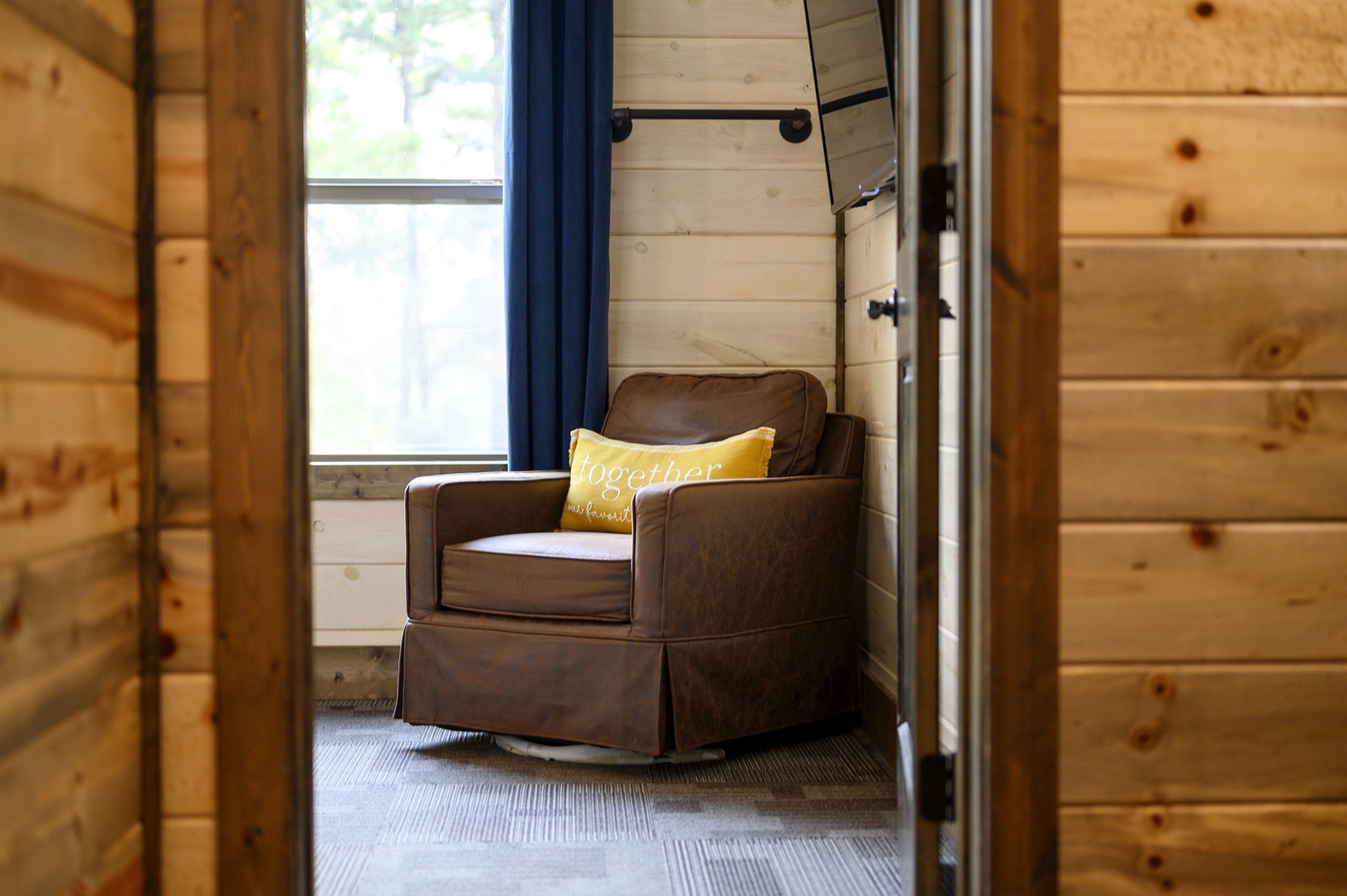 Step into your cozy reading nook where natural light and plush seating invite you to unwind with a book and breathe in the peaceful cabin charm.