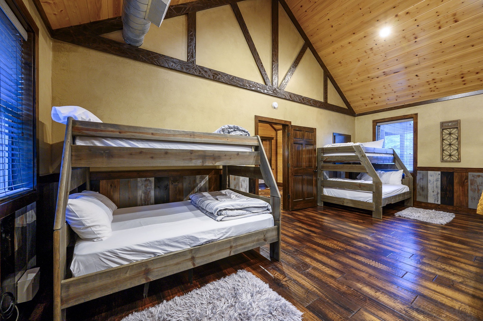 Spacious bedroom with rustic charm featuring two sturdy bunk beds beneath soaring vaulted ceilings and exposed beams—perfect for groups and families.