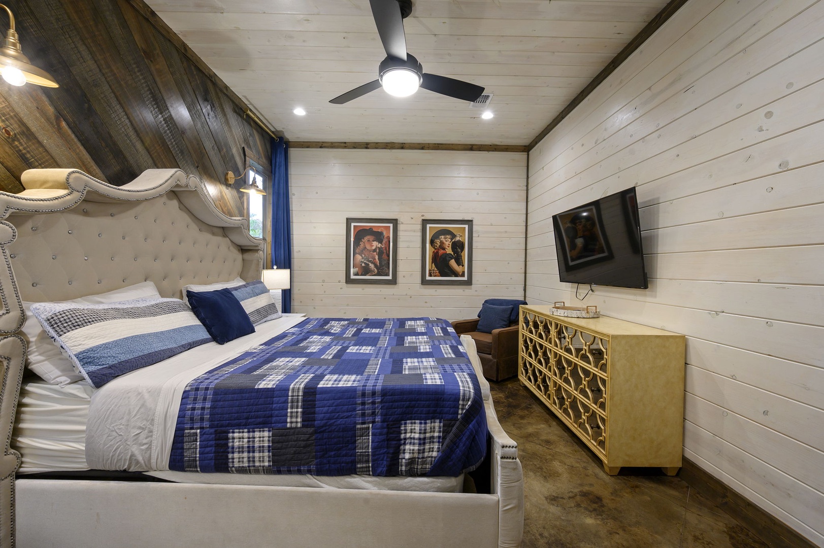 Sink into your plush upholstered bed surrounded by stylish shiplap walls and nautical blue accents. The cozy farmhouse charm meets modern comfort, with a ceiling fan for those warm nights and your own wall-mounted TV for entertainment.