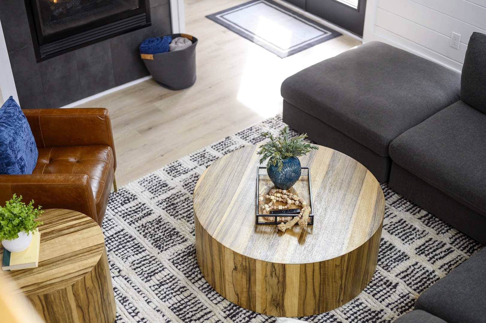 Unwind in your stylish living space featuring a plush grey sofa, rich leather chair, and stunning round wood coffee table.