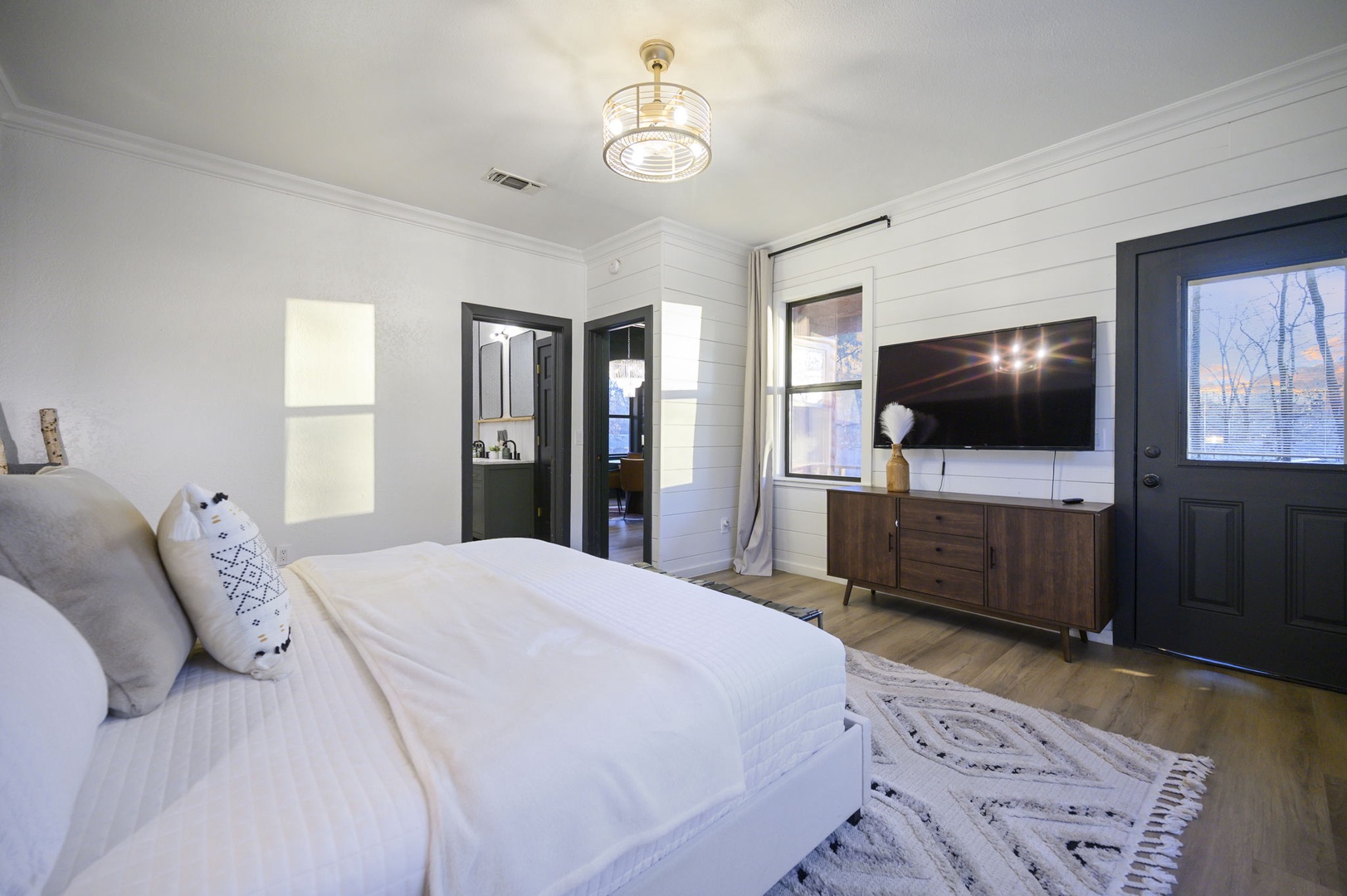 Sink into crisp white linens in your stylish retreat, where modern comfort meets rustic charm with warm wood floors and thoughtful touches.