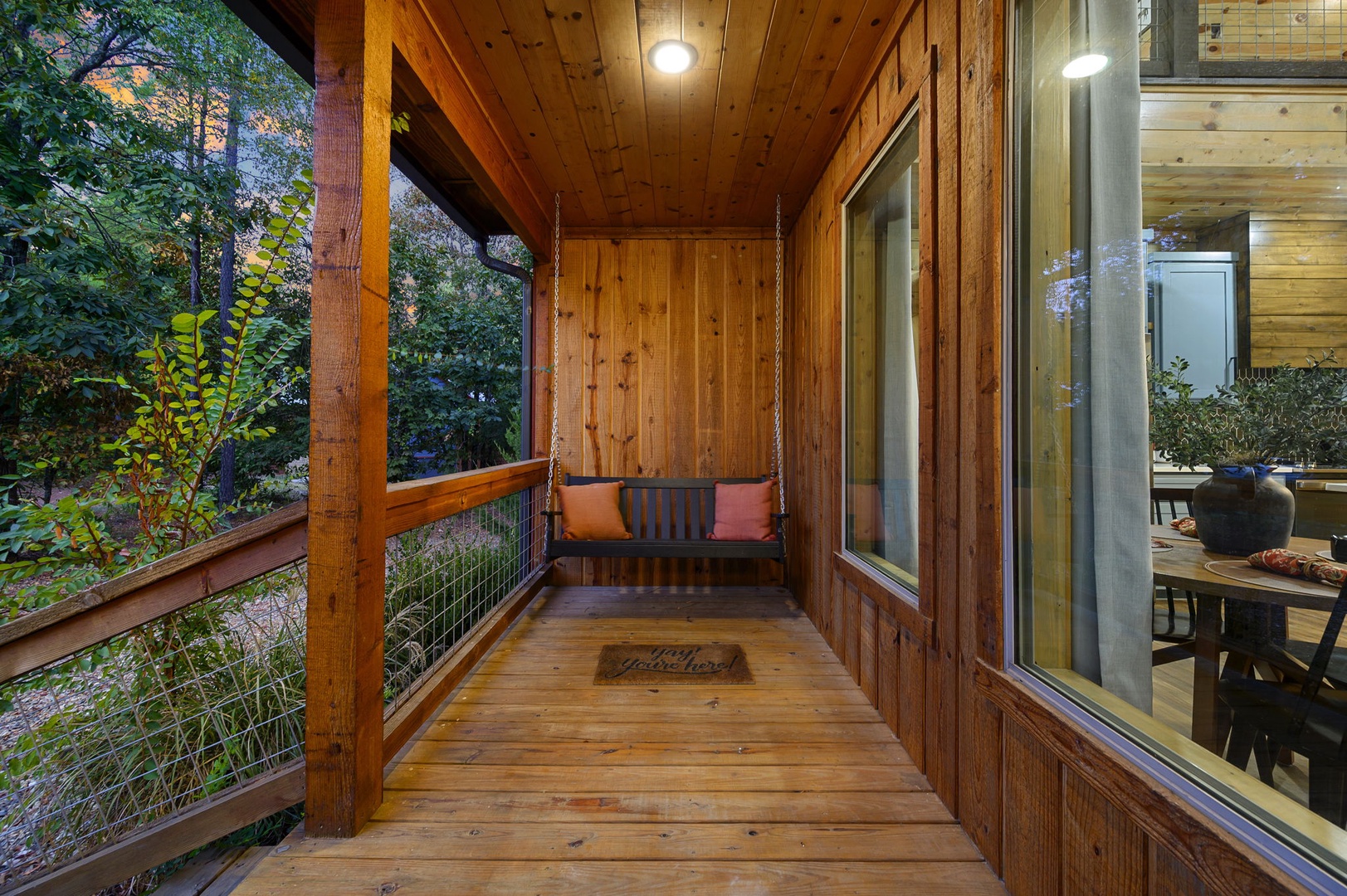 Swing gently on your private balcony, surrounded by warm wood and lush greenery. This peaceful perch invites you to unwind with the forest just beyond the railing.
