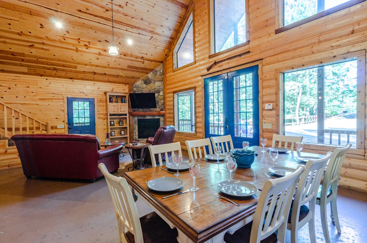 Picture yourself dining together in this stunning open-concept cabin, where soaring wood ceilings and wall-to-wall windows flood the space with natural light, while your fireplace crackles nearby.