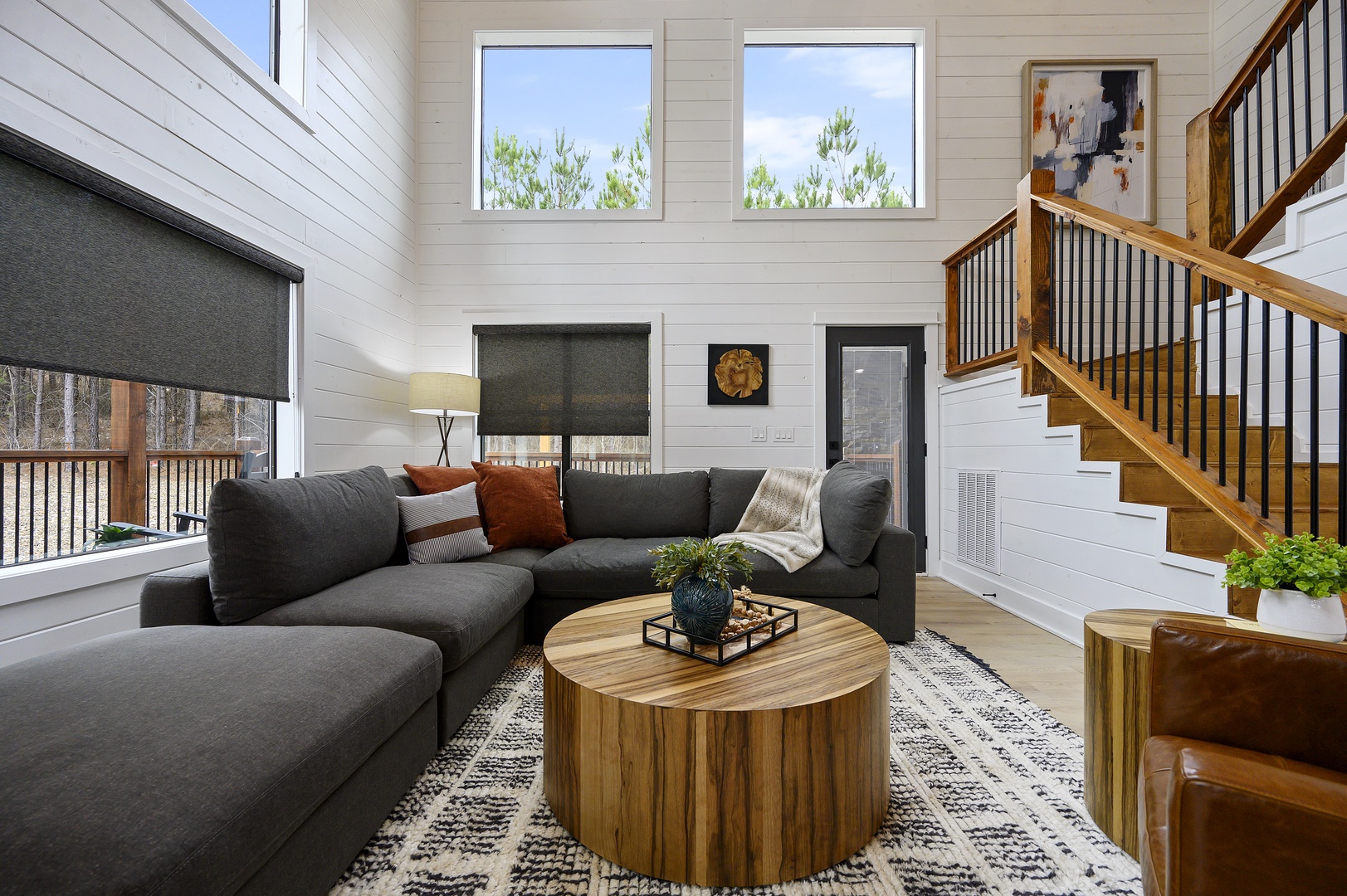 Unwind in your spacious living room with plush sectional seating, natural wood accents, and soaring ceilings that create an airy, welcoming atmosphere.