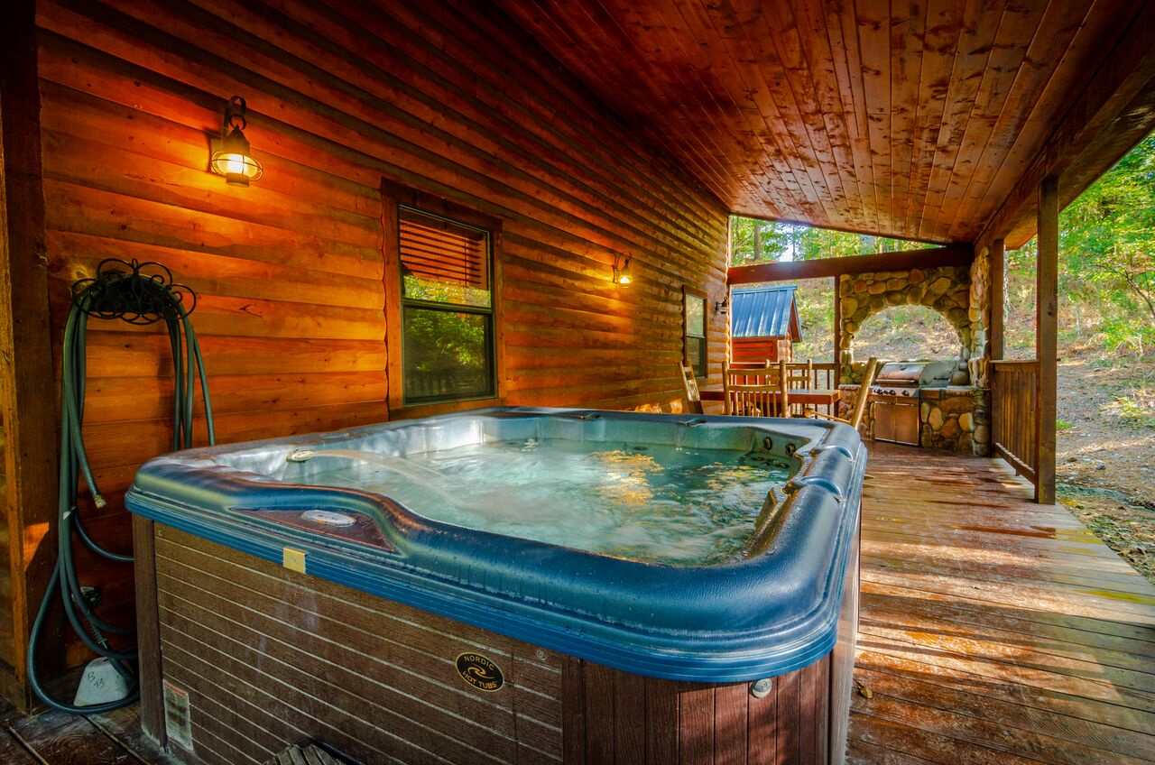 Slip into your private hot tub under the rustic wood ceiling, with a cozy stone fireplace and forest views creating a perfect retreat after exploring the area.