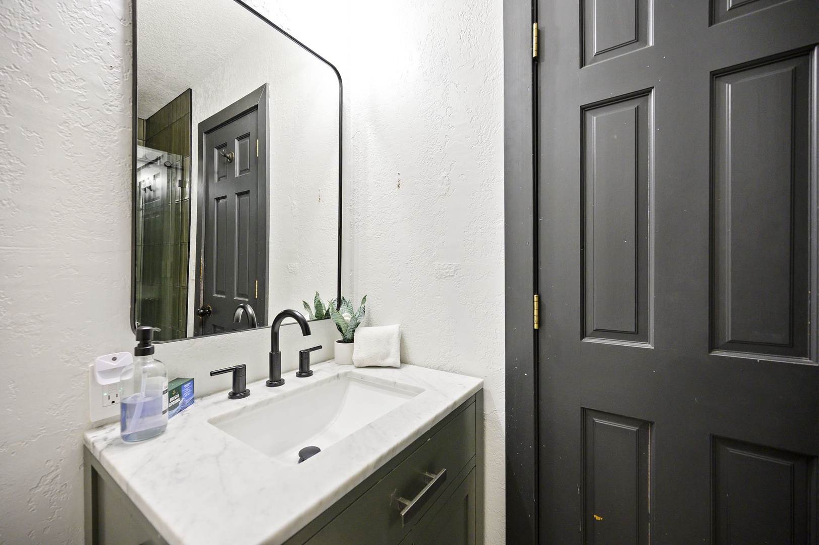 Freshen up in your stylish bathroom featuring a marble vanity, modern fixtures, and thoughtful touches like fresh greenery to start your day right.