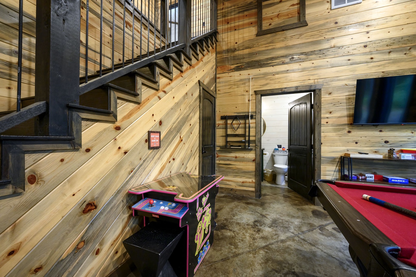 Your entertainment hub features a pool table and classic arcade for fun-filled evenings with friends and family in this rustic wood-paneled retreat.