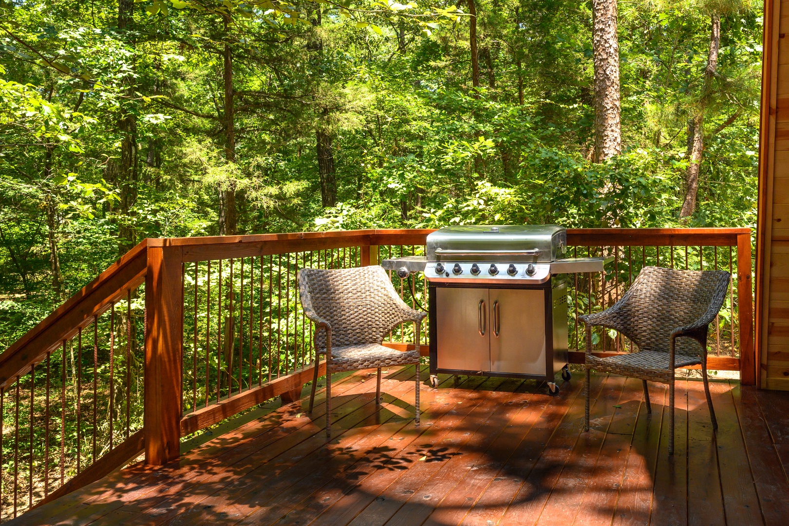 Picture yourself grilling on your private deck, surrounded by lush forest canopy. Two cozy seats invite you to savor morning coffee or evening meals while sunlight filters through the trees—a perfect retreat for nature lovers.