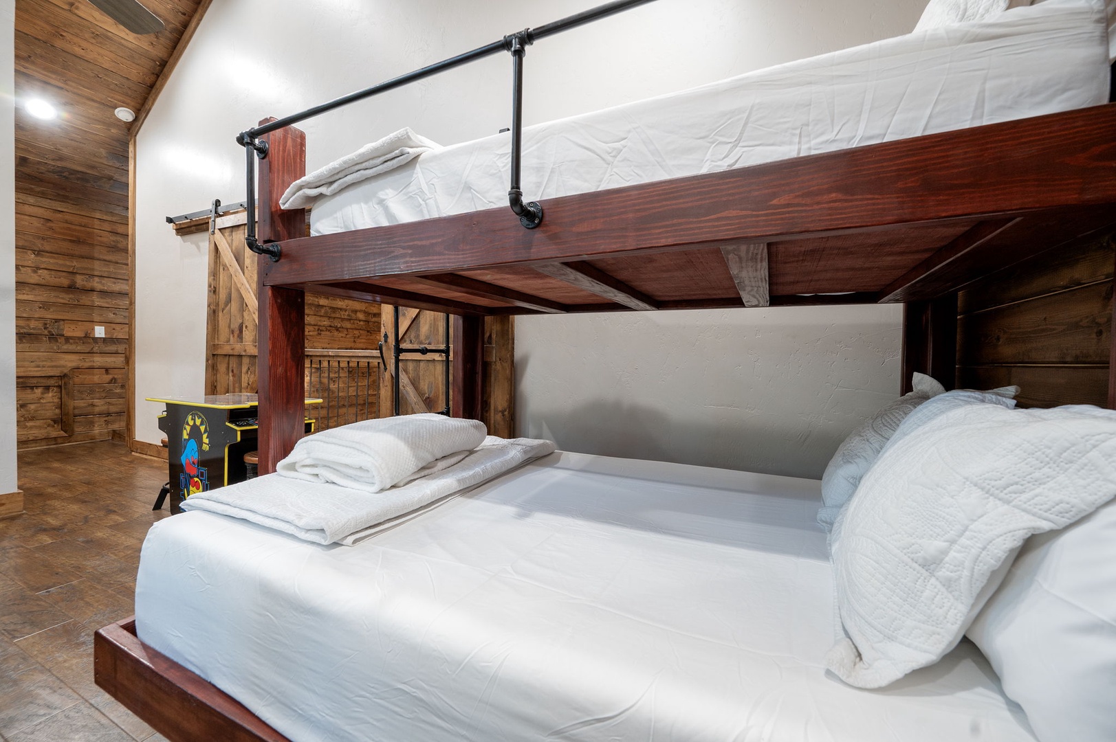 Your unique bunk room features custom-built beds with crisp linens and stylish pipe railings, blending rustic wood accents with modern comfort for a cozy, memorable stay.