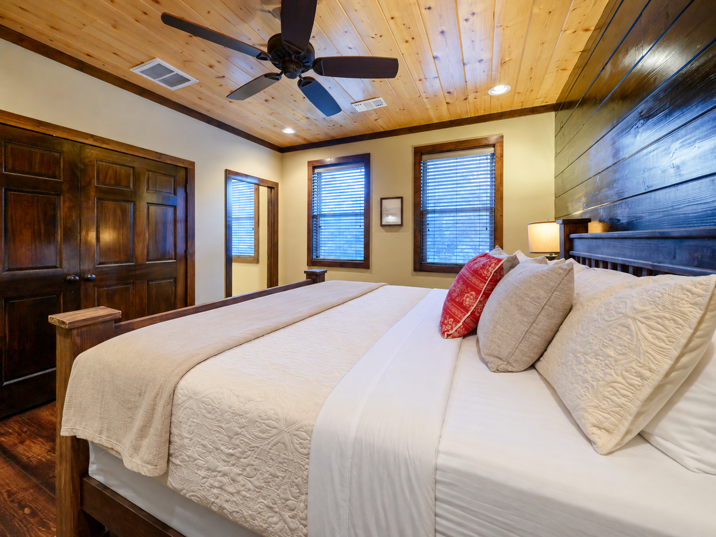 Slip into crisp linens under a warm wood-planked ceiling. This inviting bedroom features a plush king bed, charming accents, and windows that let in gentle natural light.