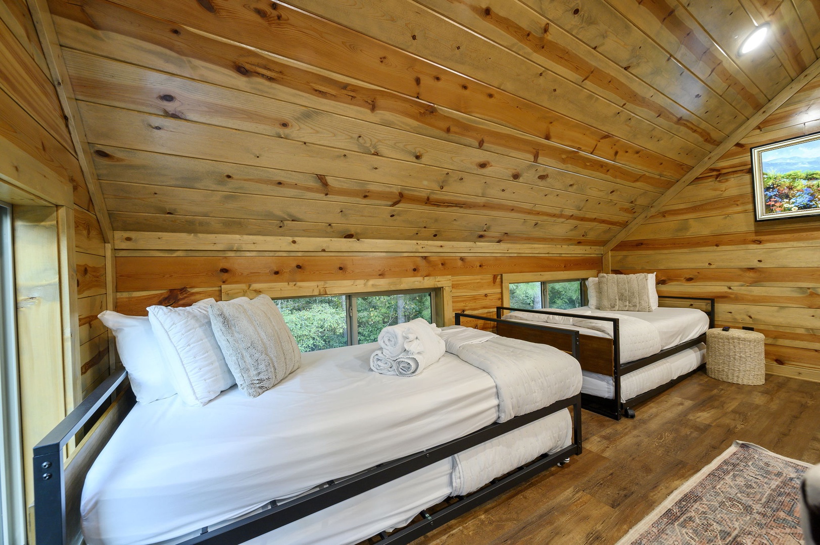 Step into your cozy wooden retreat with warm pine walls and vaulted ceilings that wrap around you like a natural embrace, where soft bedding and towels await after a day of exploring.