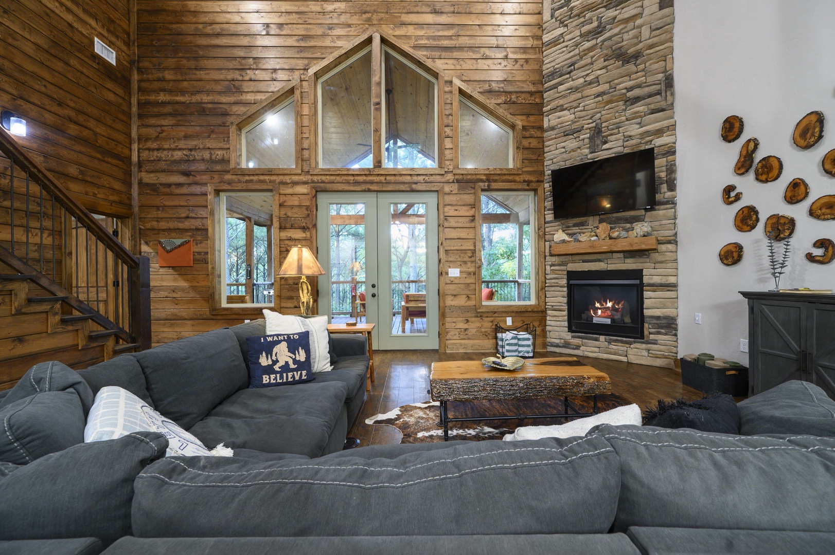 Sink into your plush sectional by the stone fireplace, where vaulted ceilings and soaring windows frame peaceful forest views. Warm wood tones and inviting décor make this your perfect mountain retreat.