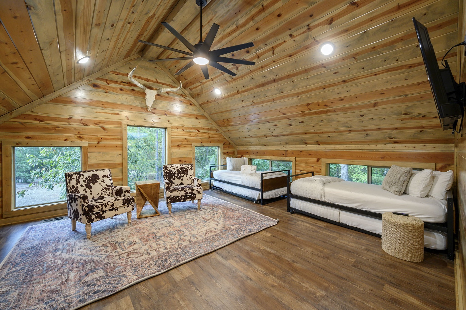 Drift off under soaring wood-paneled ceilings in this bright, spacious bedroom. You'll love the rustic charm, cozy beds, and natural light streaming through windows that overlook peaceful greenery.