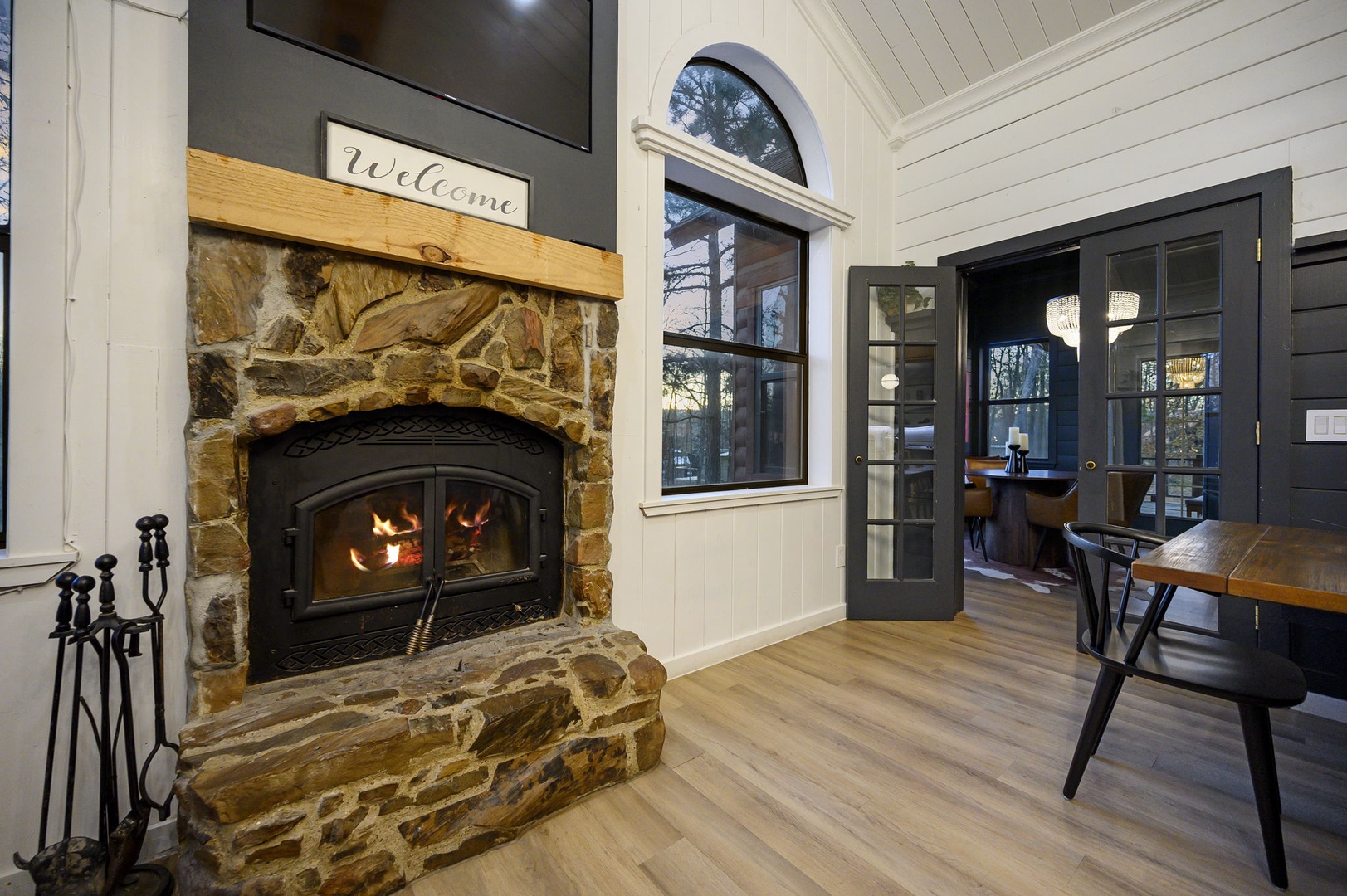 Cozy up by the crackling stone fireplace with a welcome sign that sets the perfect tone for your mountain retreat.