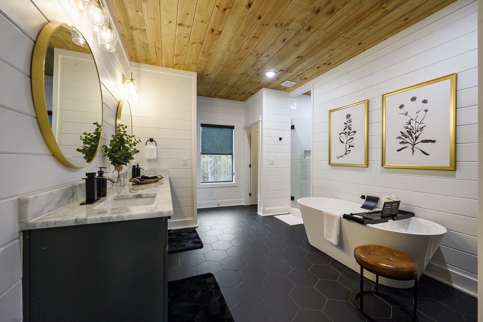 Unwind in your spa-like bathroom featuring a luxurious soaking tub, elegant gold fixtures, and warm wood ceiling for ultimate relaxation.