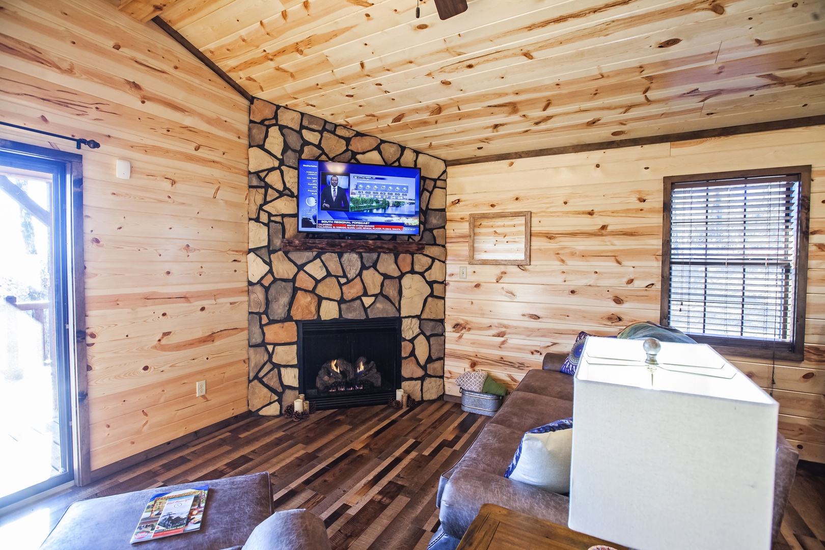 Cozy up by your stone fireplace in this warm cabin living room, complete with flat-screen TV and plush seating for perfect mountain evenings.