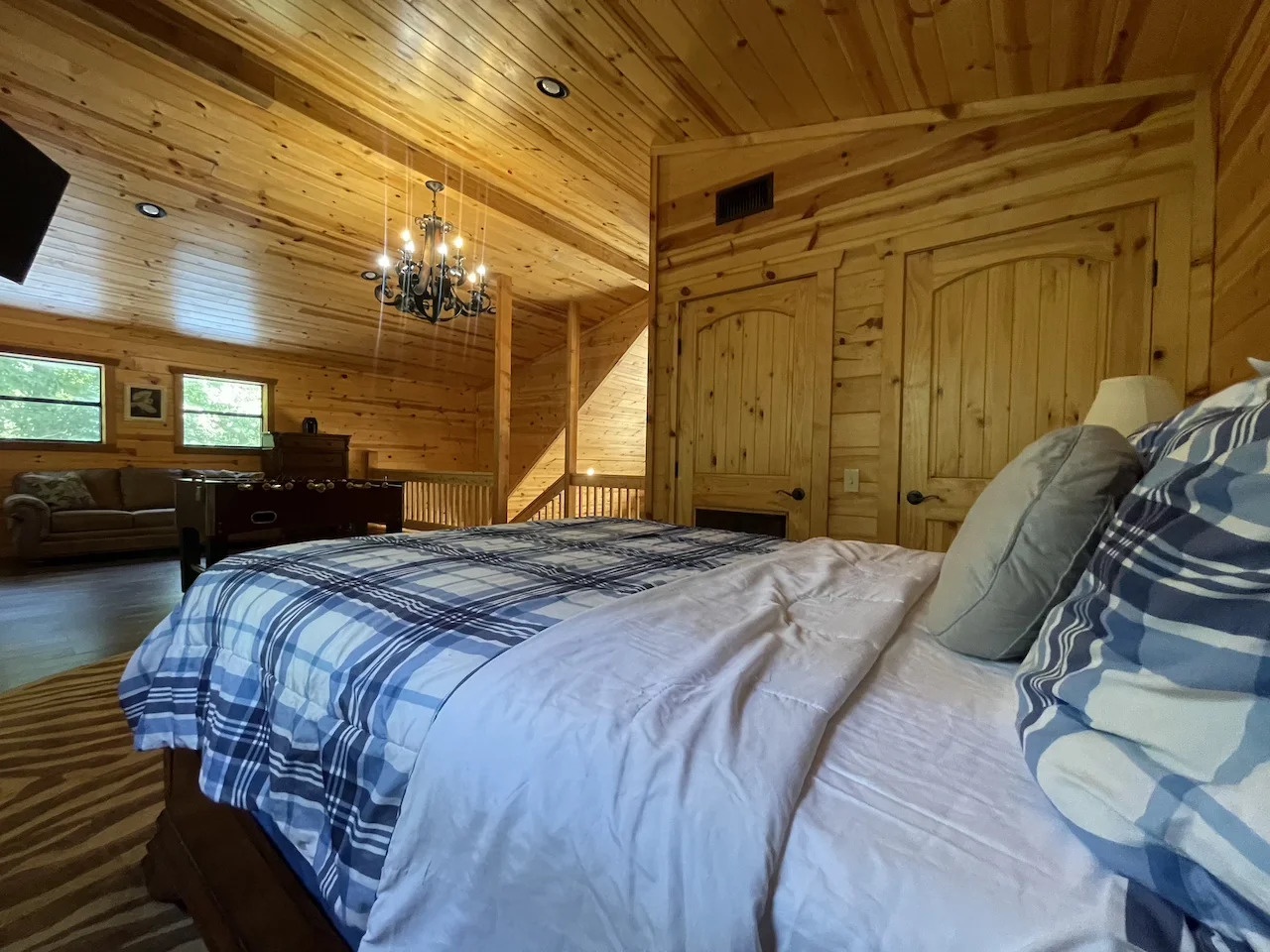 Sink into this plush bed under vaulted wood ceilings and a glowing chandelier—your peaceful retreat after a day of adventure, with cozy seating just steps away.