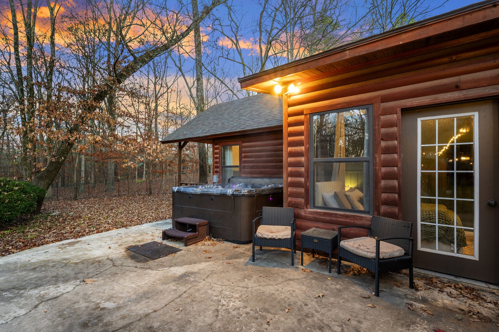Unwind in your private hot tub as twilight paints the sky, surrounded by peaceful woods and cozy outdoor seating for ultimate relaxation.