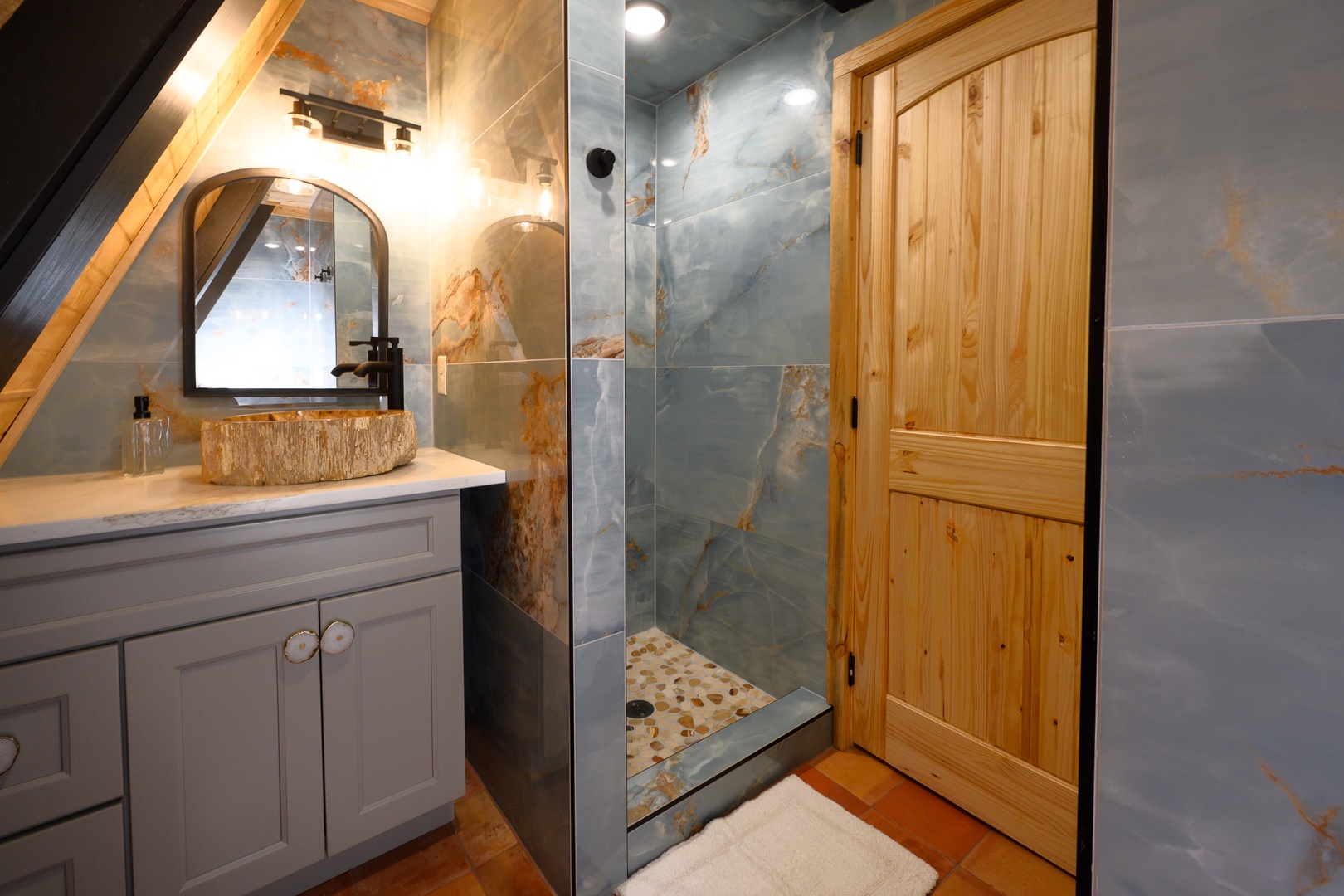 Your private bathroom blends rustic charm with modern elegance. The statement stone sink and sleek glass-enclosed shower create a spa-like retreat after a day of exploring.