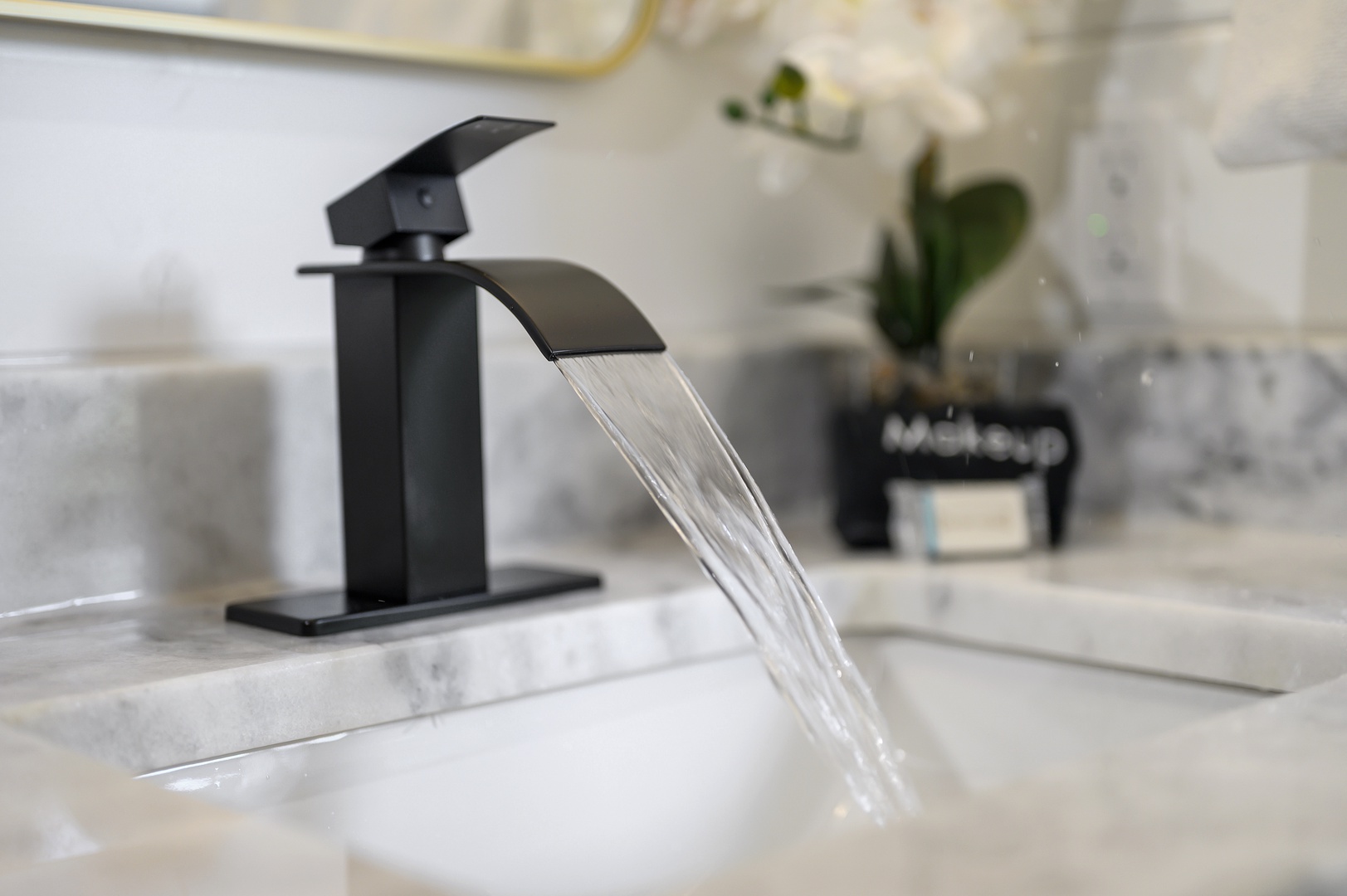Experience luxury with this sleek waterfall faucet in your elegantly appointed bathroom, where modern design meets pristine marble finishes.