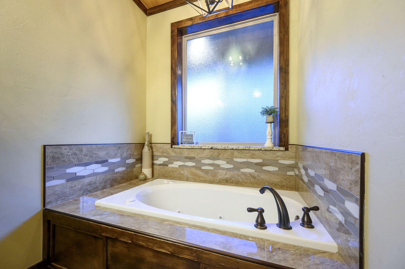 Relax in your private soaking tub surrounded by elegant tile and peaceful natural light streaming through the window above—a perfect retreat after a day of adventure.