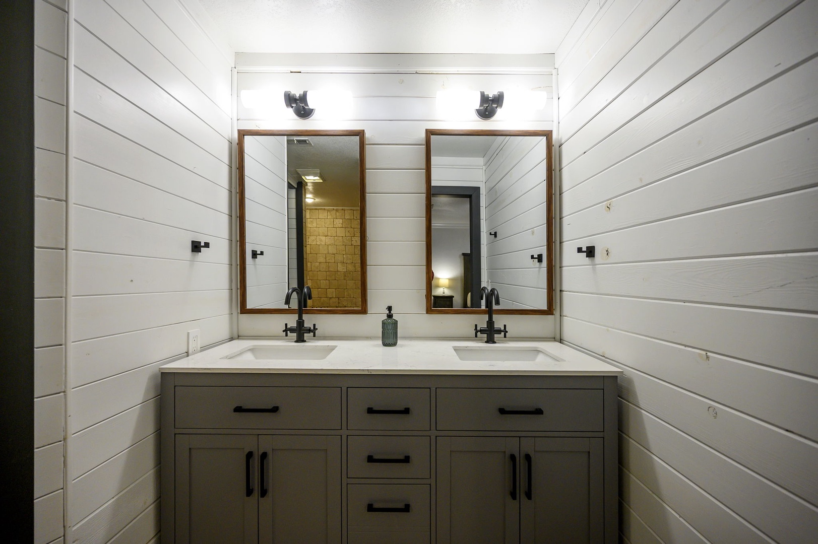 Step into your stylish farmhouse bathroom featuring dual vanities and warm wood-framed mirrors that perfectly complement the crisp white shiplap walls.