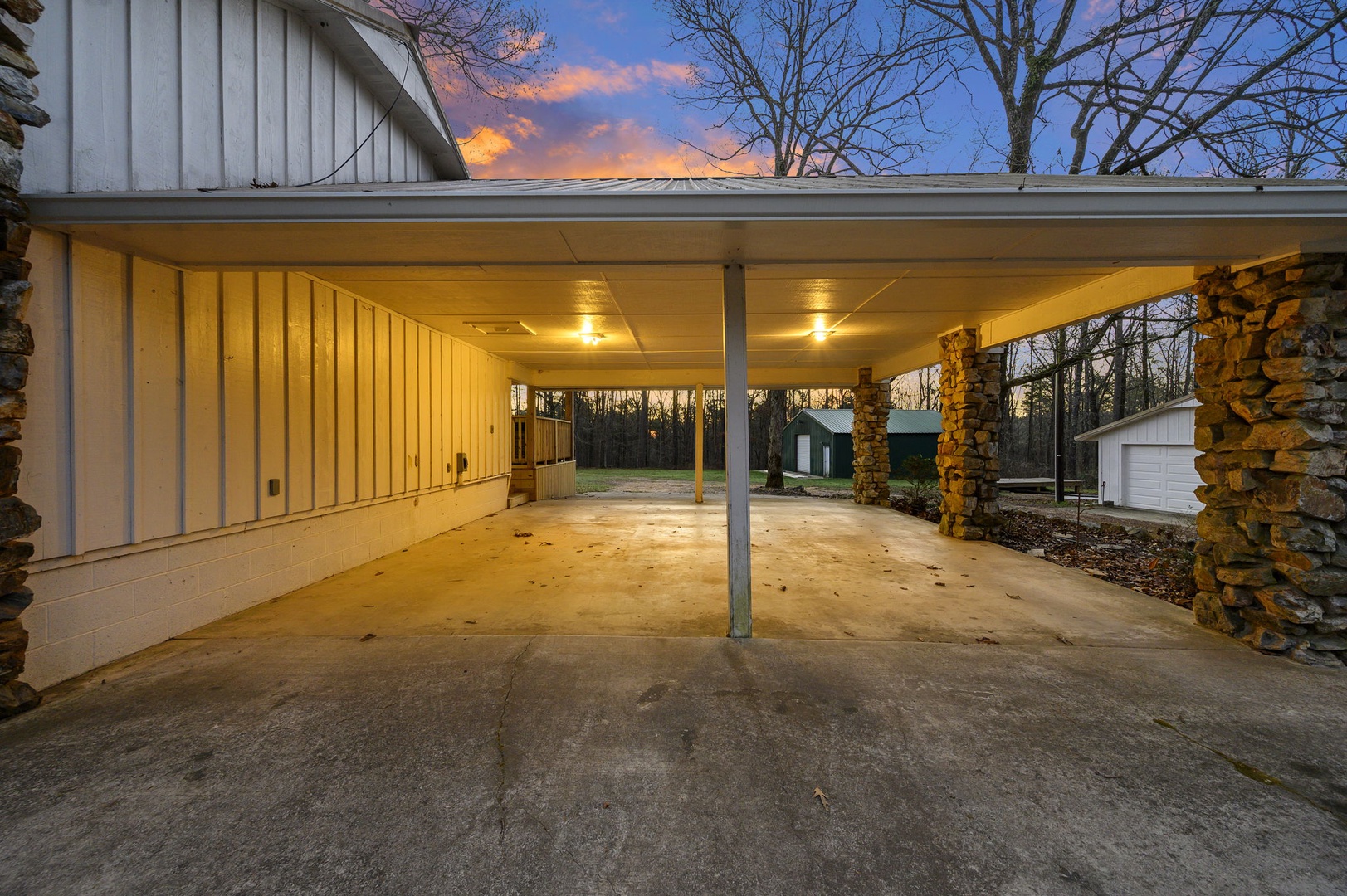Covered parking provides shelter for vehicles while dramatic evening skies create a scenic backdrop during arrival.