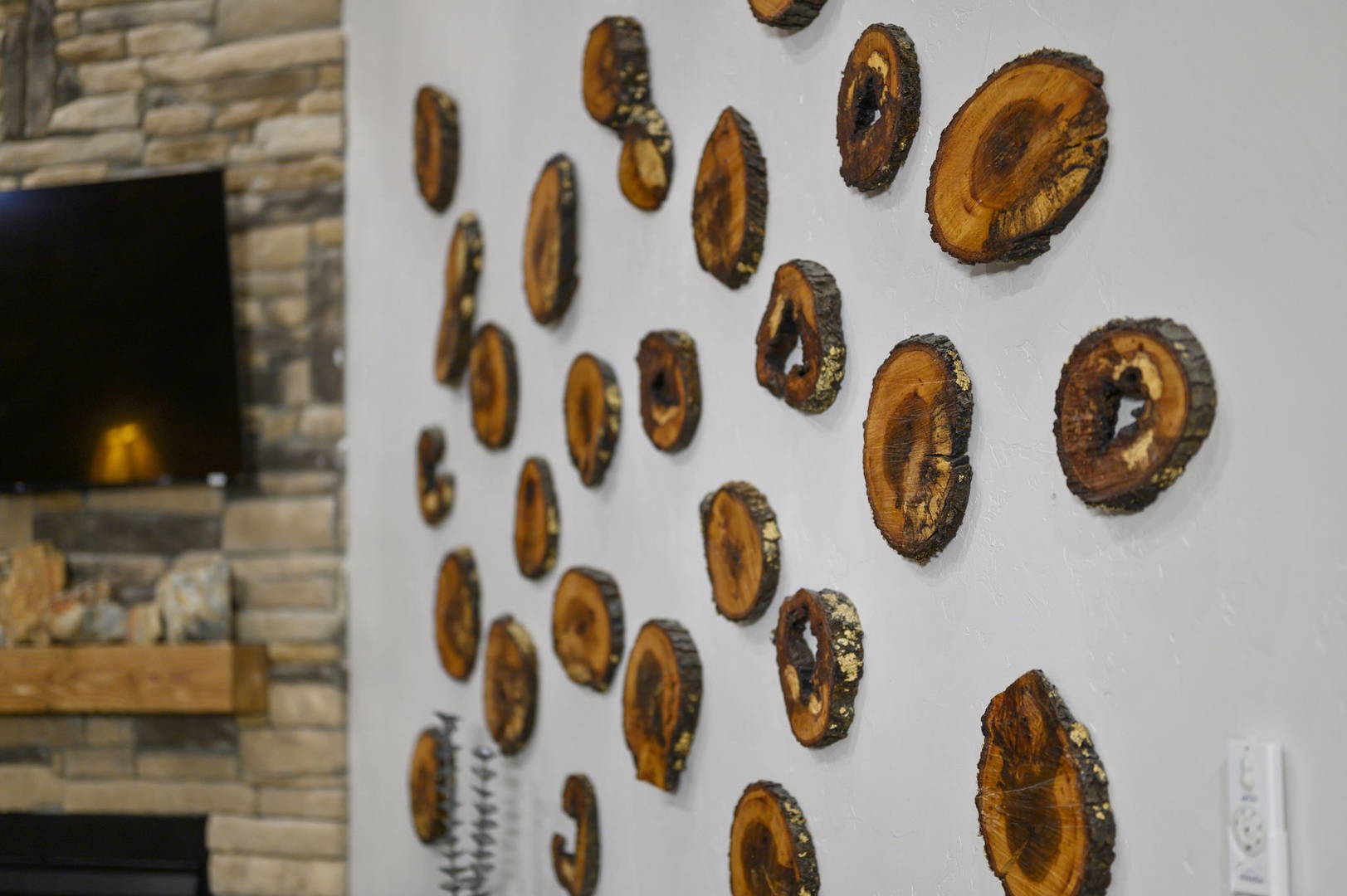 Natural wood slice wall art adds organic warmth and texture to your living space, complemented by a beautiful stone fireplace that creates a cozy gathering spot.