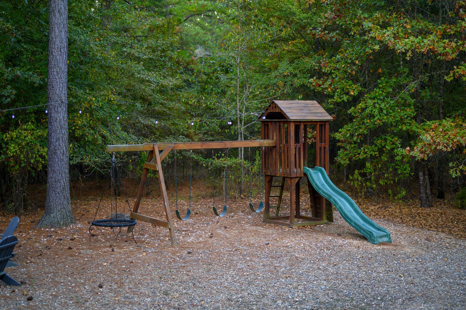 A private playground nestled among trees awaits your little explorers—complete with a wooden playhouse, slide, swings, and a basket swing for endless outdoor fun during your stay.