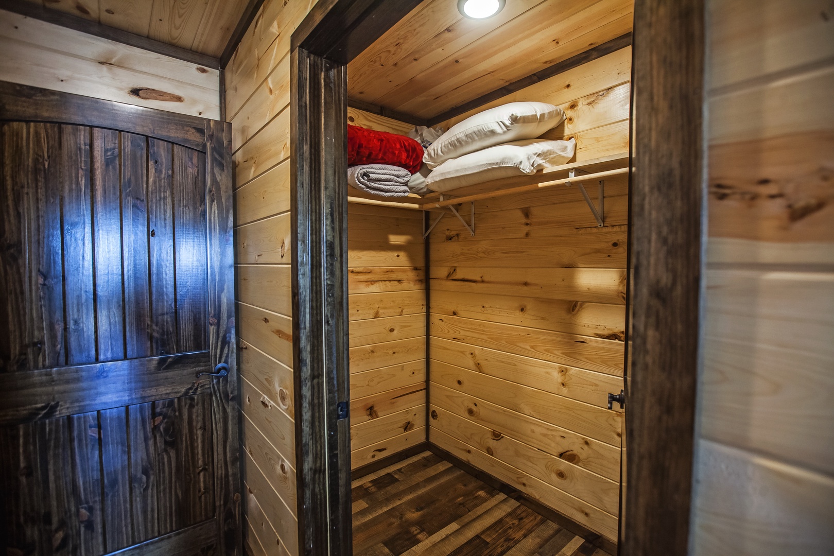 Step into your rustic walk-in closet with warm wood paneling and convenient shelving for organizing your mountain getaway essentials.