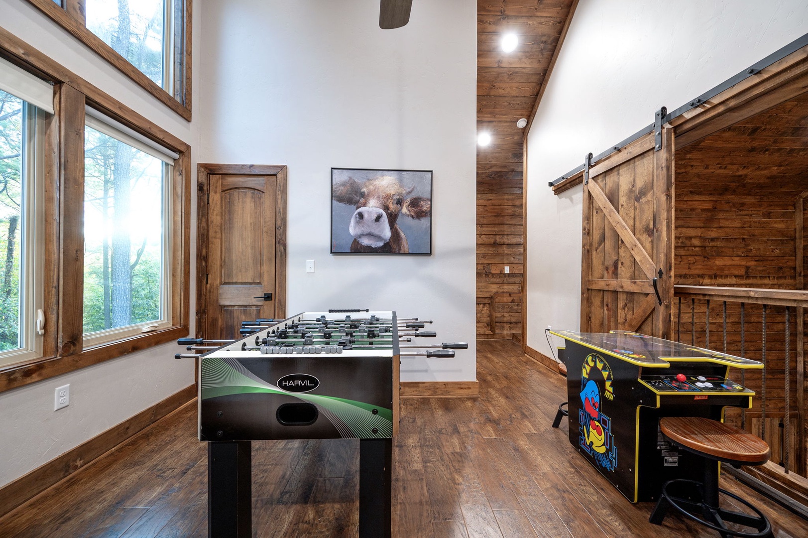 Challenge your group to a friendly foosball match in this light-filled game room, where rustic wood beams and barn doors create a warm, inviting space for playful competition.