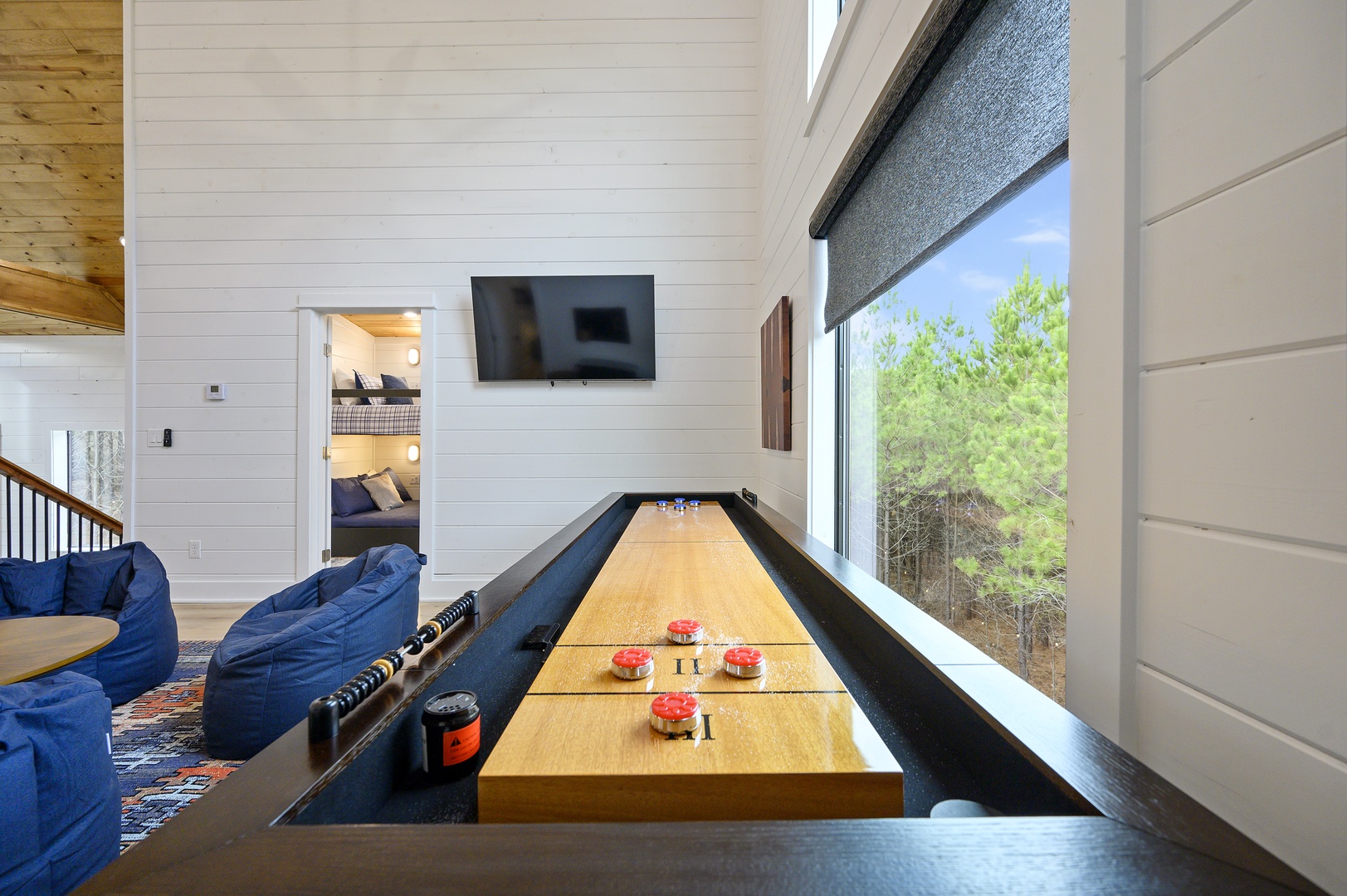 Your private game room features a sleek shuffleboard table and cozy seating, perfect for friendly competition with stunning garden views.