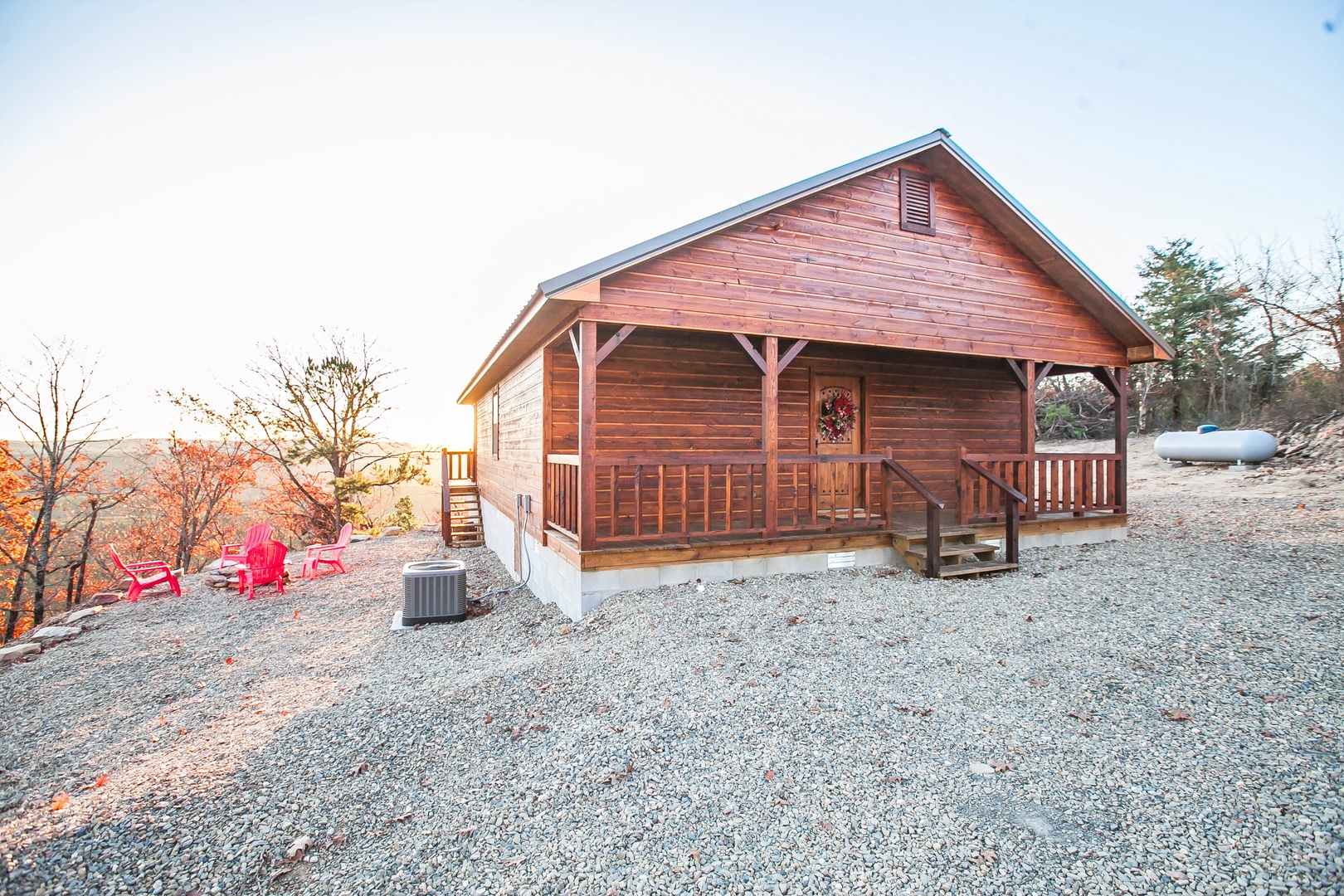 Charming log cabin with covered porch nestled among autumn trees, featuring modern amenities and peaceful mountain surroundings.
