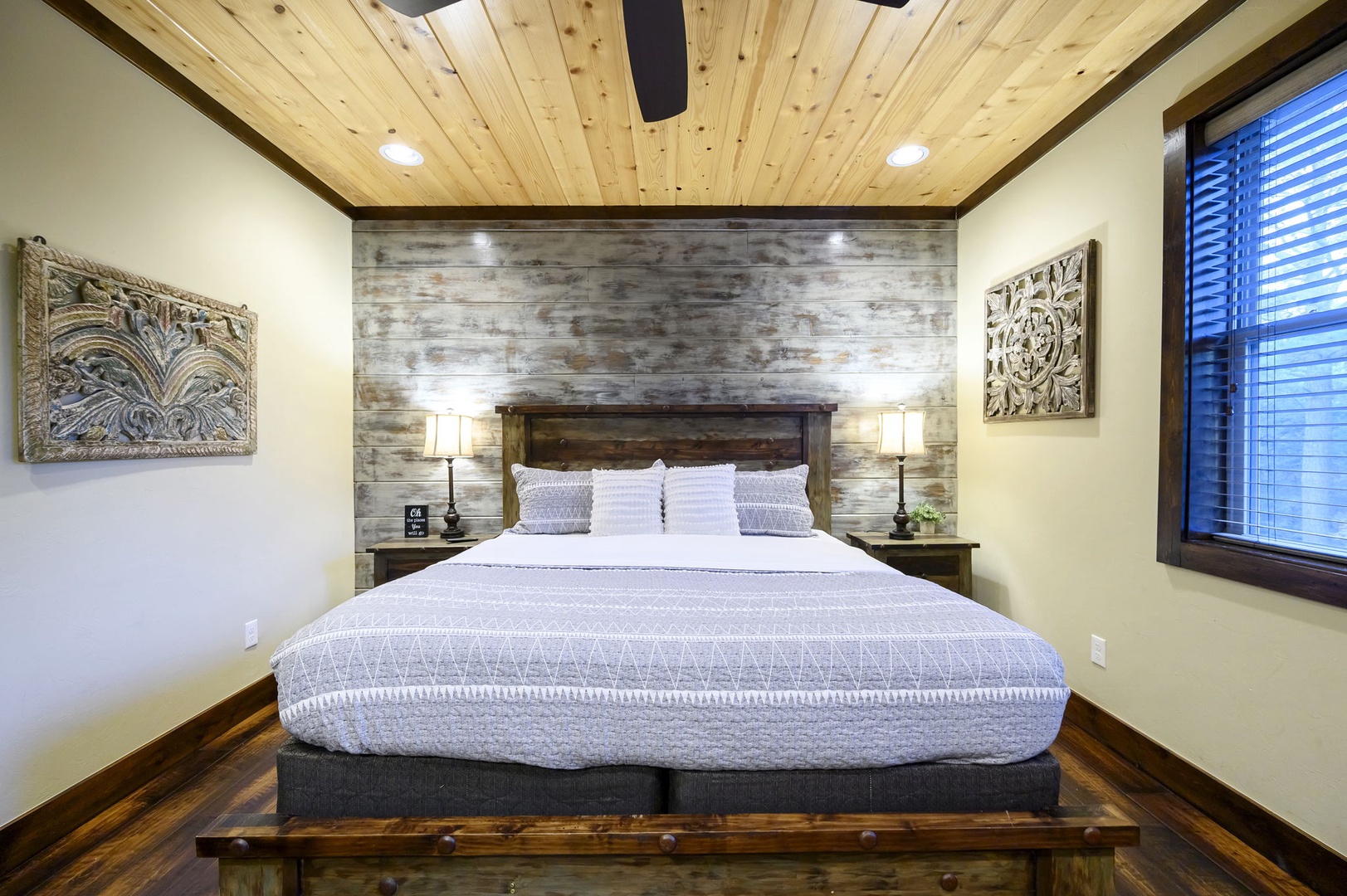Slip into your plush king bed beneath a gorgeous reclaimed wood accent wall and soaring pine ceilings. Rustic elegance meets modern comfort in your serene bedroom retreat.