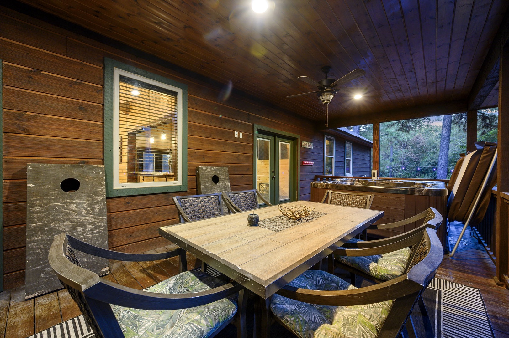 Gather around the covered patio table for meals or games, with a hot tub waiting just beyond. Warm lighting and garden views make this your perfect evening retreat.