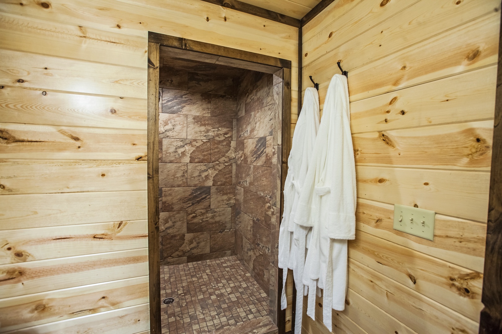 Step into your private rustic retreat with a stunning stone shower and cozy log cabin walls that create the perfect mountain escape.