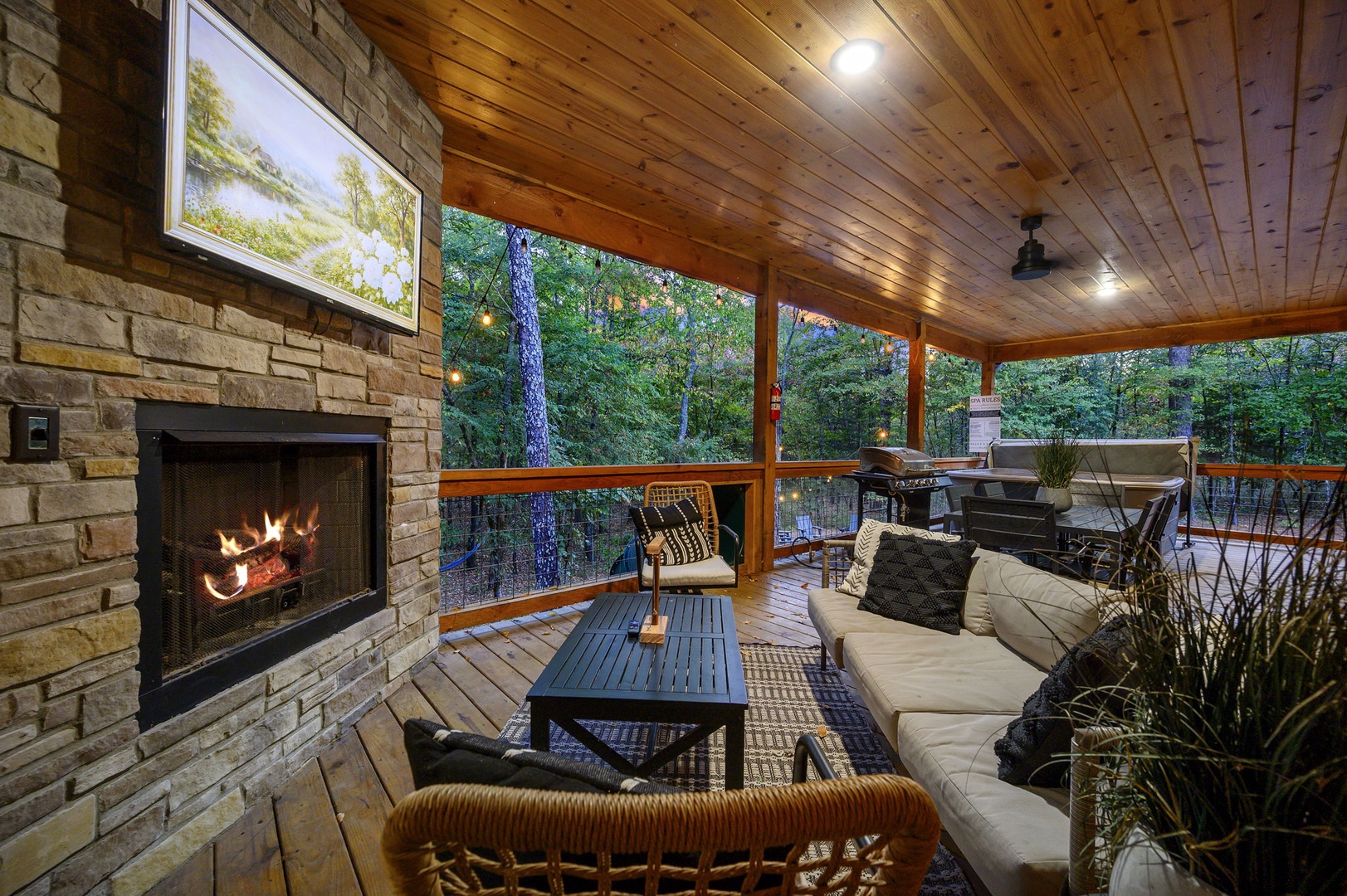 Unwind on your screened porch where a warm fireplace, cozy seating, and a peaceful forest backdrop create the perfect setting for evening conversations or quiet moments.