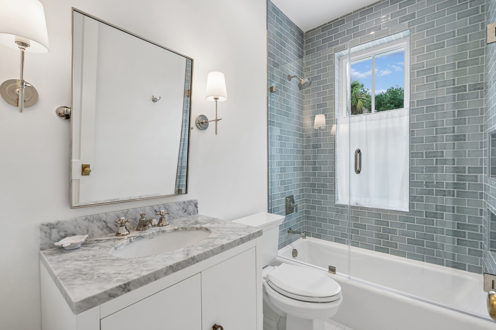 Refresh in your elegant bathroom featuring soothing sea-green subway tiles, a marble vanity, and a tub-shower combo—your personal spa retreat after a day of adventure.