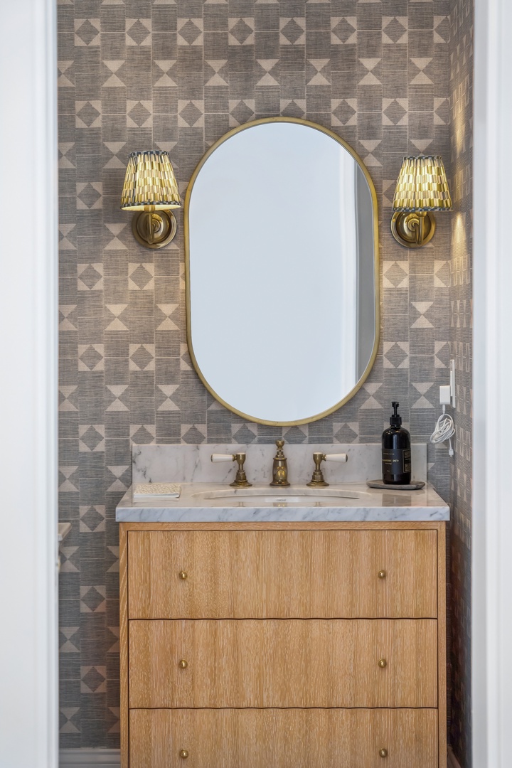 Freshen up in your elegantly designed bathroom, where geometric wallpaper and brass fixtures create a warm, sophisticated retreat just for you.