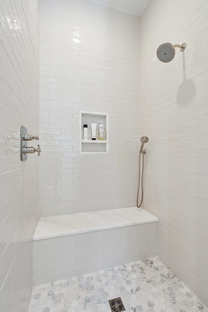 Step into your private spa-like sanctuary. Gleaming white subway tiles frame the walk-in shower, while a built-in bench invites you to relax under the rainfall showerhead.