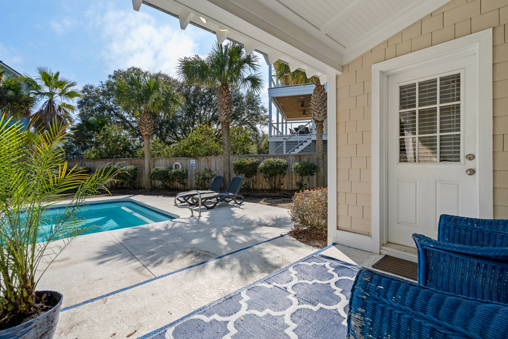 Step onto your private covered patio where tropical palms frame your sparkling pool, creating the perfect sunny retreat.