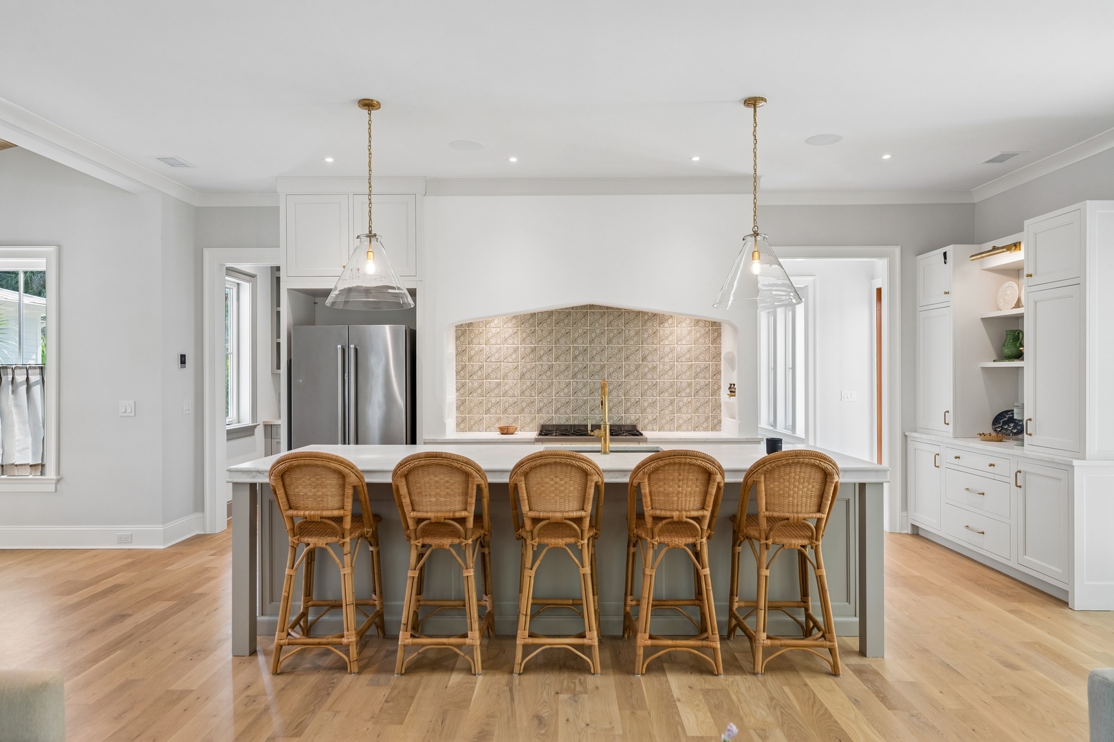 Gather with loved ones at this spacious kitchen island, where elegant pendant lighting and warm wood tones create the perfect spot for morning coffee or evening conversation.
