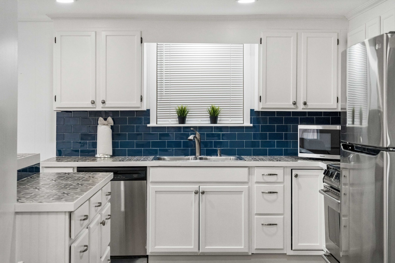 Your fully-equipped kitchen features sleek white cabinets, stunning blue subway tile backsplash, and stainless steel appliances for memorable meal preparation.