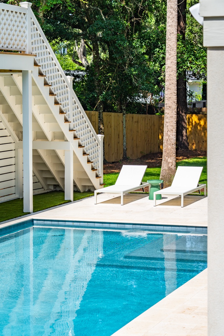 Slip into the sparkling pool and lounge on your private deck, surrounded by lush trees and modern architectural details that create a serene backyard escape.