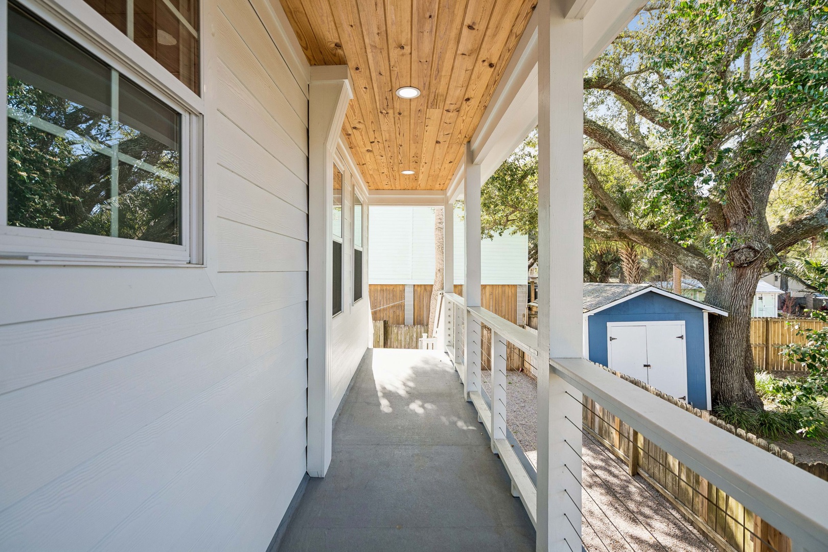 Step onto your private covered balcony with warm wood ceiling and white railings, perfect for morning coffee surrounded by leafy neighborhood charm.