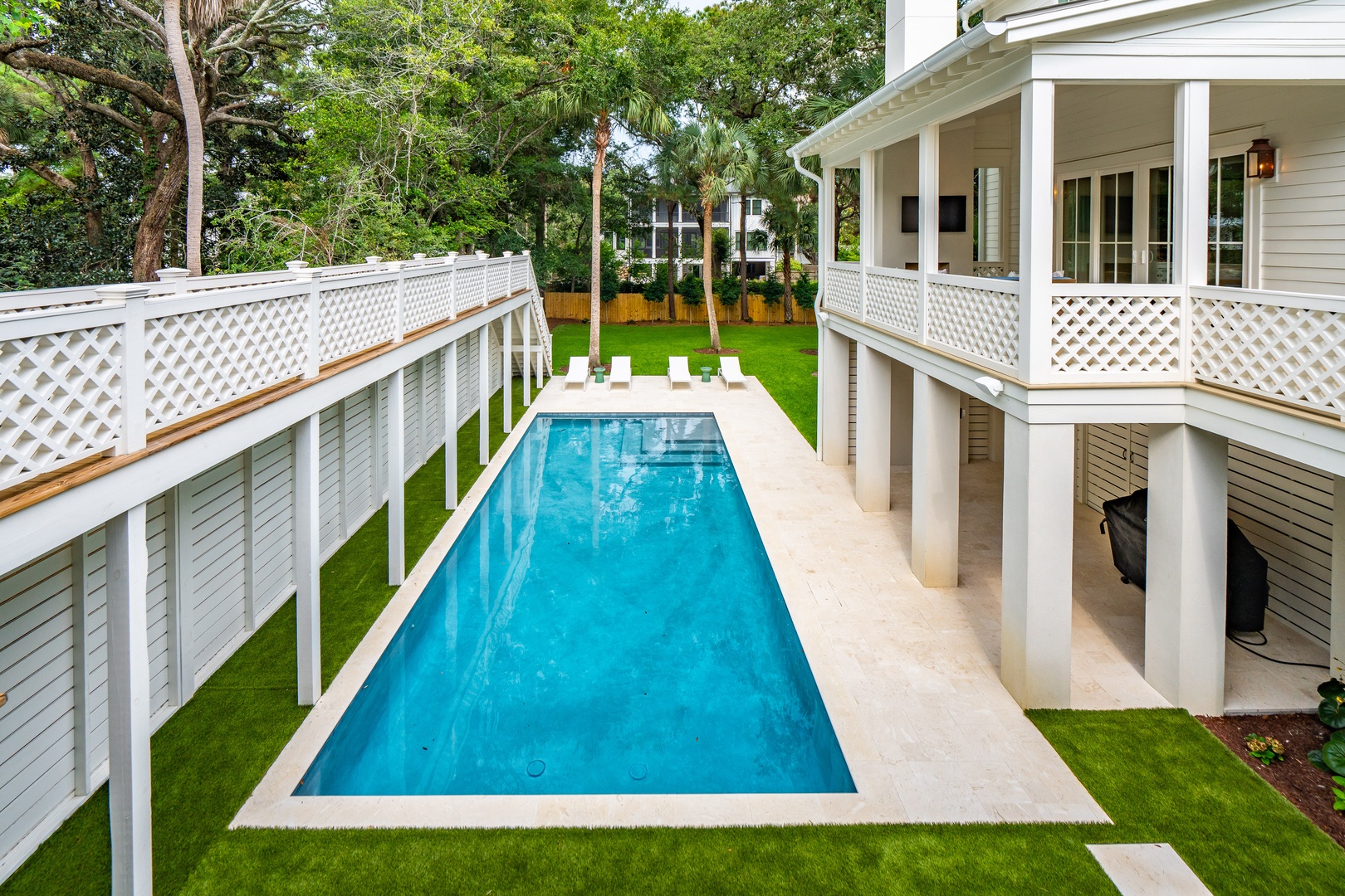 This elegant property features a pristine pool surrounded by lush green lawns and shaded by mature trees, creating your own private retreat with wraparound balconies overlooking the water.